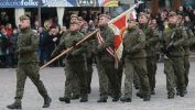 Grupa maszerujących żołnierzy ze sztandarem po płycie rynku w Rzeszowie