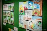 Wystawa. Kolorowe rysunki dzieci przyczepione na zielonej tablicy. 
