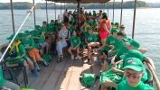  Grupa dzieci na łodzi. Są ubrani w zielone koszulki. Siedzą.