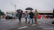  Grupa osób idzie pod parasolami na punkcie granicznym 