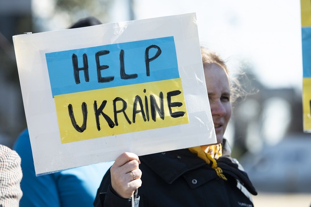 Zdjęcie kobiety trzymającej tabliczkę z napisem Help Ukraine