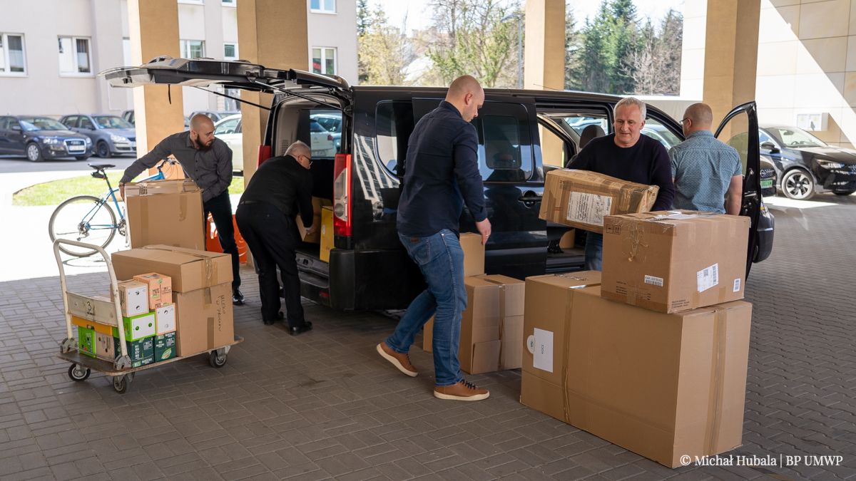 Pracownicy urzędu marszałkowskiego rozpakowują samochód z darami dla walczącej Ukrainy