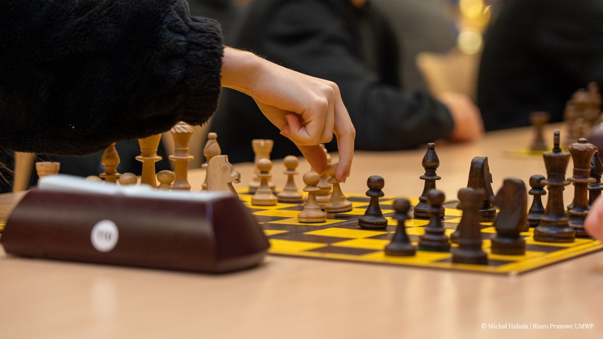 Zbliżenie na rękę trzymającą pionek do gry w szachy.